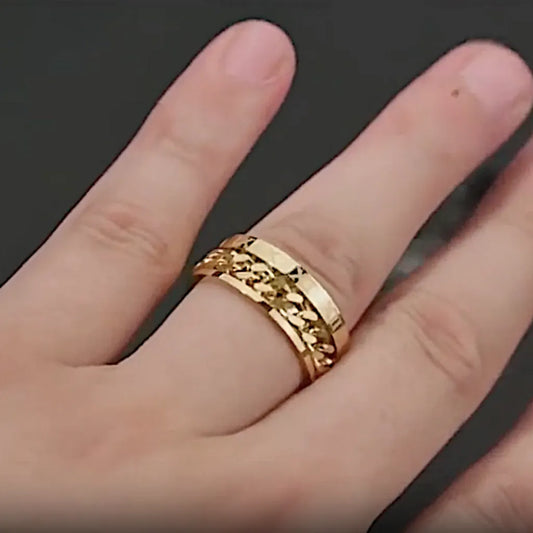 Bague chaîne romaine dorée portée à la main : design épais et élégant, chaîne rotative et gravures visibles.