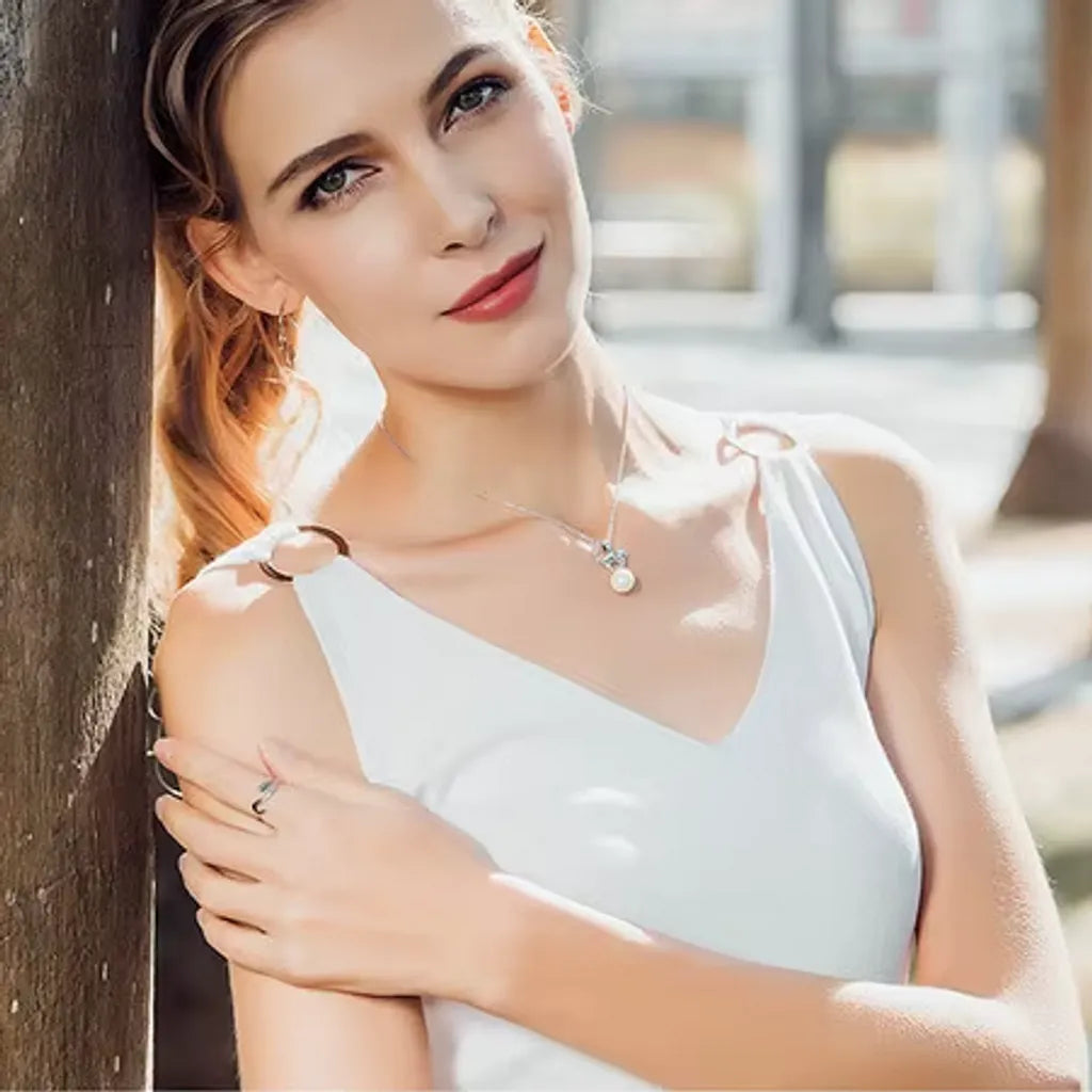 Femme en plein air avec bague chat argent design ouvert, bijou tendance sublimant une tenue blanche décontractée chic.