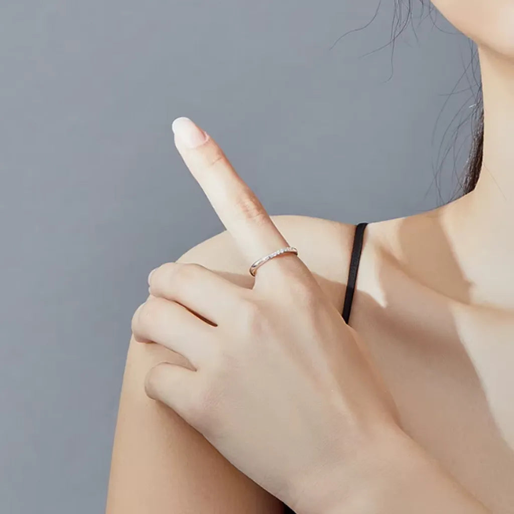 Bague en argent 925 avec zircones blanches, capturant la lumière sur un index droit, la main est délicatement posée sur l'épaule.