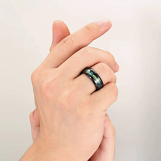 Bague homme couleur noire portée à l’annulaire, mise en valeur des reflets nacrés sur une peau claire.
