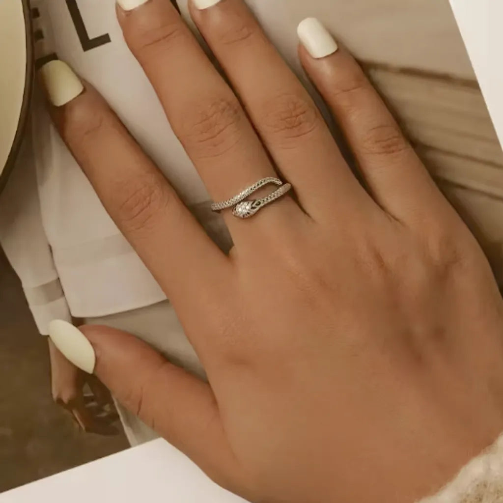 Zoom sur bague serpent vipère argent 925 portée, mettant en valeur les détails gravés et les pierres zircones vertes.