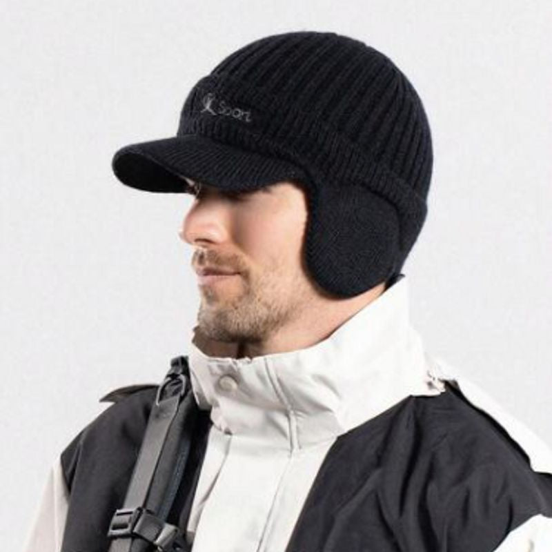 Bonnet à visière noir de sport d'extérieur Lake Placid avec cache-oreilles, vue de profil sur la tête d'un jeune homme habillé chaudement d'un anorak