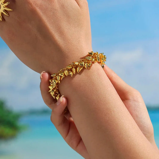 Bracelet Amorina doré au poignet, breloques cœur visibles, ambiance estivale chic au bord de l’eau.