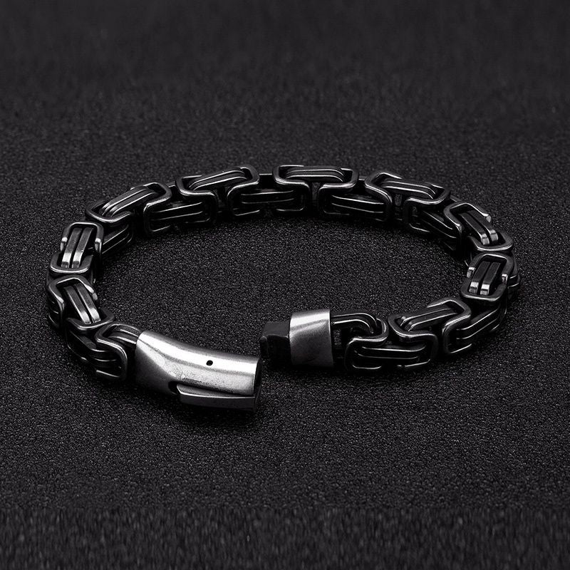 Bracelet biker avec chaîne à maillons complexes et originaux avec fermoir clip à ressort sécurisé en acier inoxydable 316L, posé sur un plan de travail sombre de couleur gris foncé - coloris vintage argent vieilli