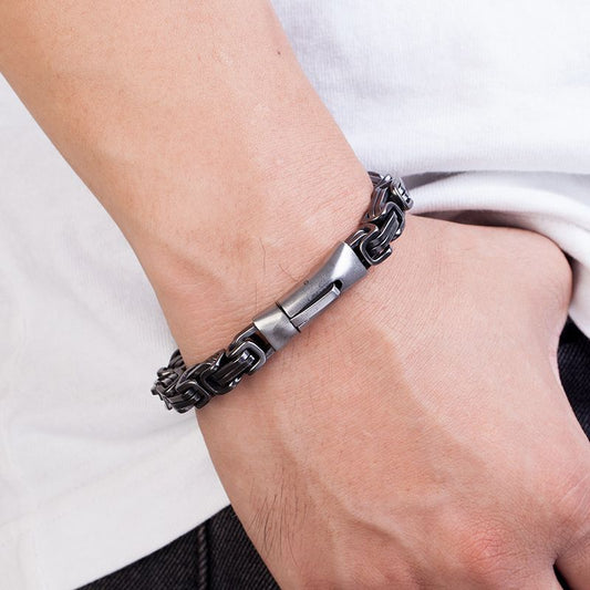 Bracelet biker avec chaîne à maillons complexes de sept millimètres avec fermoir sécurisé en acier inoxydable sur le poignet droit d'un homme ayant le pouce dans la poche avant de son jean - coloris acier argent vieilli