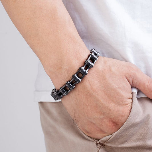 Bracelet biker chaîne de moto et fermoir en acier inoxydable présenté autour d'un poignet d'un homme la main dans la poche - coloris argent vieilli