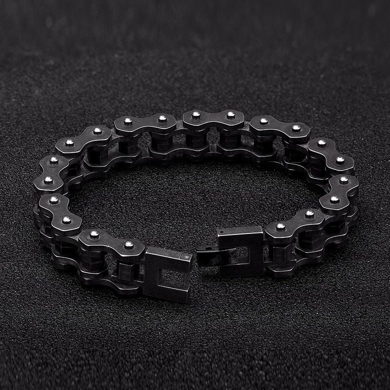 Bracelet biker chaîne de moto à maillons écrous de 13 mm et fermoir crochet ouvert à clip en acier inoxydable posé sur un plan de travail noir - coloris de l'acier argent vieilli