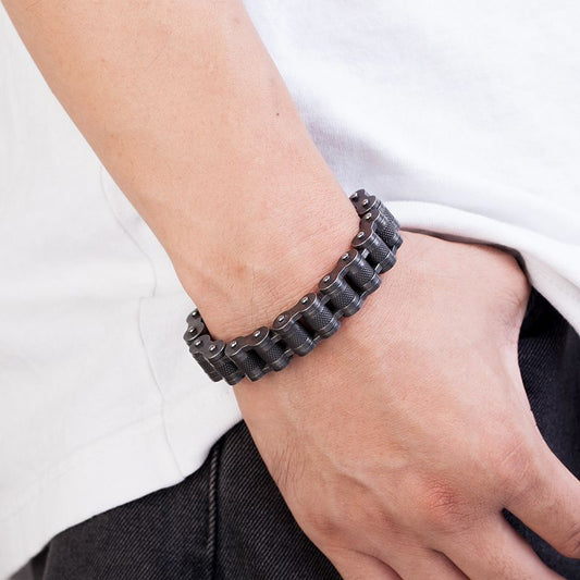 Bracelet biker avec maillons moletés et fermoir en acier inoxydable présenté autour d'un poignet d'un homme - coloris argent vieilli