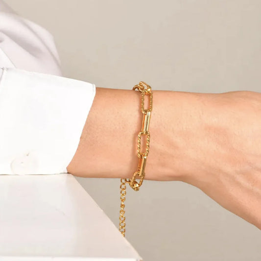 Le bracelet Calista doré porté au poignet, maillons torsadés bien visibles et chaînette ajustable avec gravure 18K tombant délicatement.
