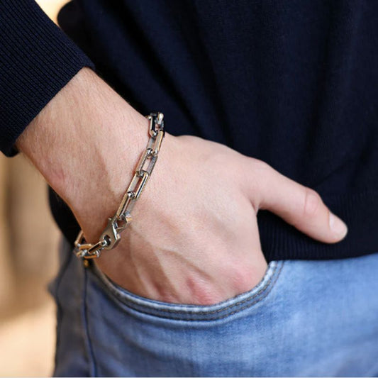 Bracelet chaîne d'ancre à maillons rectangulaires sur le poignet d'un homme ayant sa main dans la poche avant de son jean - acier inoxydable de coloris argent