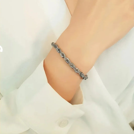 Bracelet Cordelia argenté porté sur poignet féminin, chemise blanche élégante, rendu délicat et maille corde brillante.