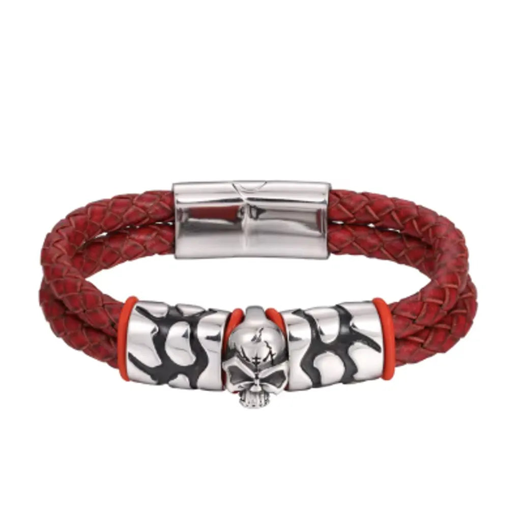 Bracelet en cuir tressé rouge avec un fermoir magnétique en acier inoxydable argenté, photographié sur un fond blanc. Le centre du bracelet arbore une tête de mort argentée et deux anneaux métalliques avec des motifs modernes. La couleur rouge vif associée aux détails métalliques crée un bijou au style affirmé et dynamique, idéal pour les amateurs de mode audacieuse.