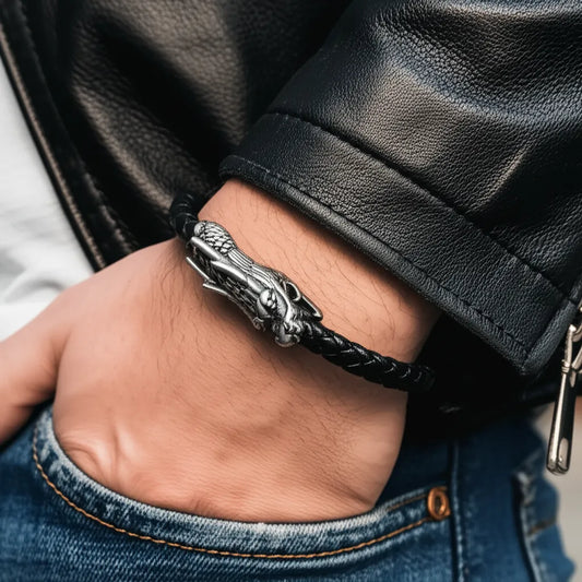Gros plan du bracelet Dragon Ouroboros en cuir noir au poignet d'un homme au blouson noir de profil, la main dans la poche de son jean.