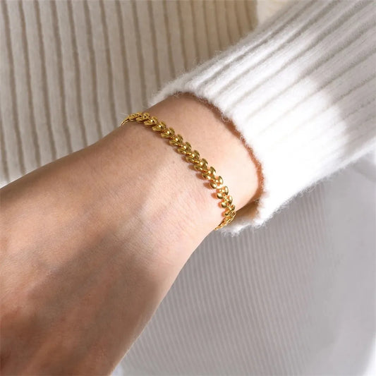 Bracelet Épi de Blé en acier doré porté sur poignet féminin, avec pull blanc – mise en valeur du contraste doux et du raffinement du bijou.