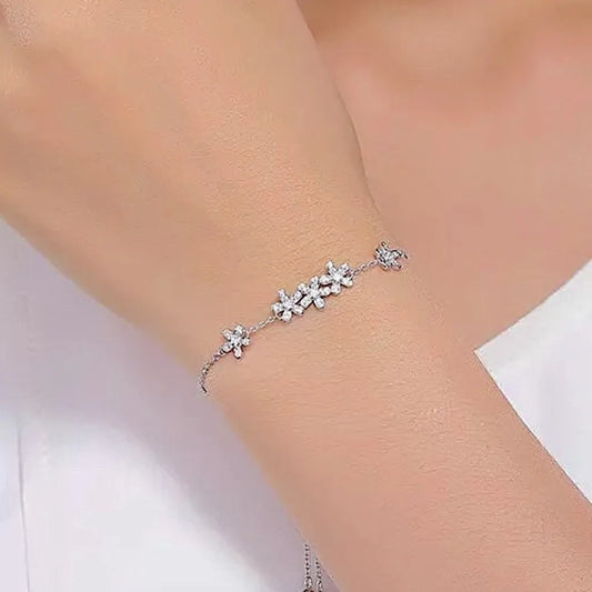 Bracelet Marguerita en argent 925 porté au poignet gauche, chaîne fine maille forçat, 5 marguerites serties de zircone blanche, effet lumineux sur peau nue.