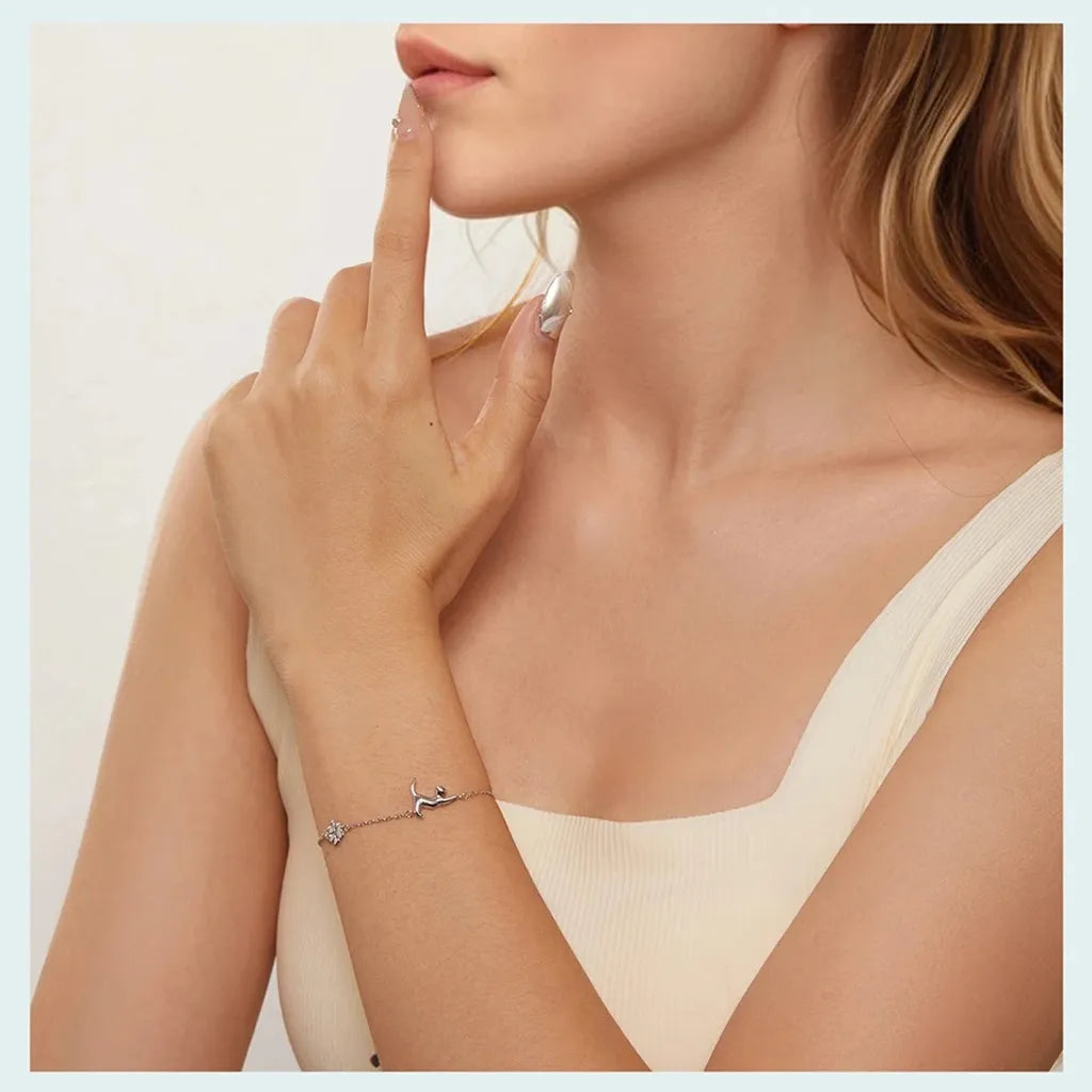 Bracelet Mia motif chat porté vue de profil, chat en posture étirée tourné vers le poignet, patte en contrepoids, finition argent 925 plaqué platine.