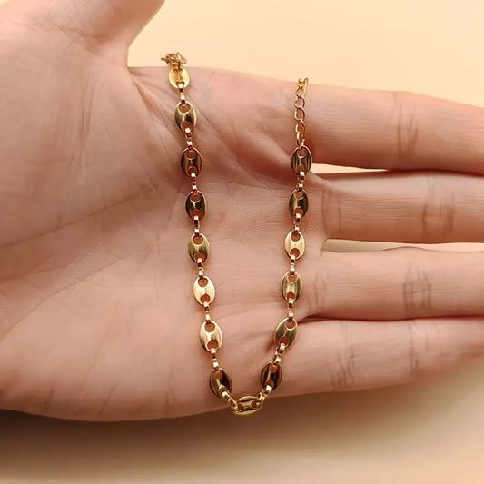 Bracelet Nysa doré en acier inoxydable enroulé autour des doigts de la main gauche, présentation naturelle révélant la souplesse et la brillance du bijou.