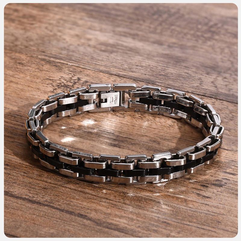 Bracelet homme fermé Steel présenté sur un table vintage en bois - sa splendeur éclate grâce notamment à la brillance de son acier inoxydable de couleur argent et noir - fermoir à clapet pour une grande sécurité