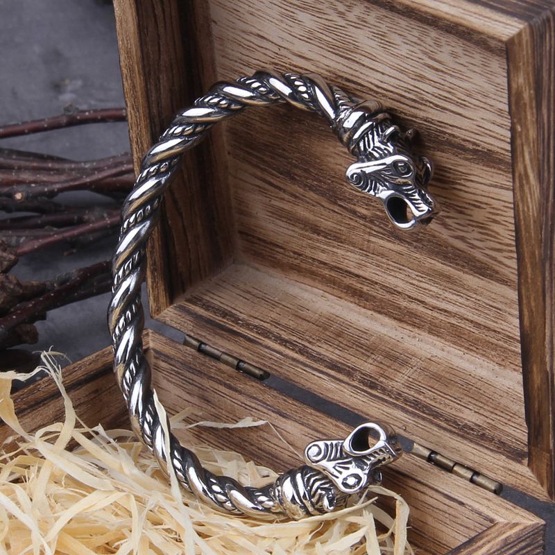 Bracelet torque viking avec tĂȘtes d'ours nordique en acier inoxydable - jonc ouvert torsadĂ© appuyĂ© sur sa boite cadeau ouverte en bois foncĂ© signĂ© Vikings - Manchette coloris argent