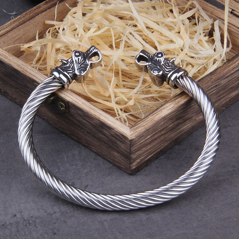 Bracelet torque viking avec ours nordique en acier inoxydable - jonc ouvert celte torsadé appuyé sur l'angle de sa boite cadeau ouverte en bois foncé signé Vikings - Manchette cùble coloris argent