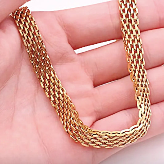 Collier Altina doré présenté dans une main, focus sur la souplesse et la brillance de la maille.