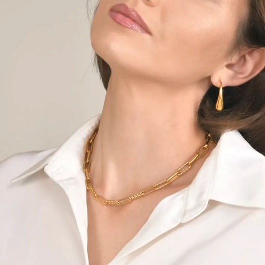 Collier Calista en acier doré porté au cou, maillons trombone torsadés visibles en détail, profil élégant et allure lumineuse.