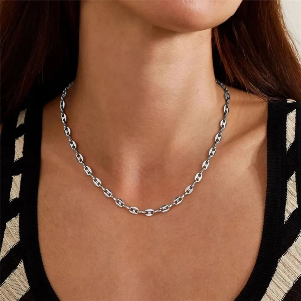 Variation argentée du collier Nysa, portée avec une robe noire et blanc cassé aux découpes graphiques. Style urbain chic et minimaliste.