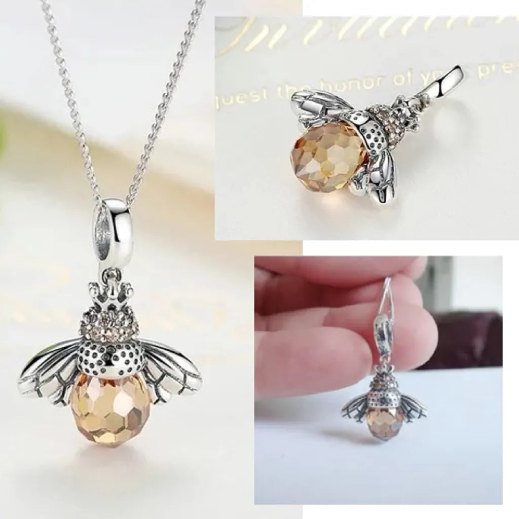 Collier fin pendentif abeille en argent 925 avec zircones, cristal facetté jaune miel, présenté entre les doigts pour illustrer la taille réelle du bijou.