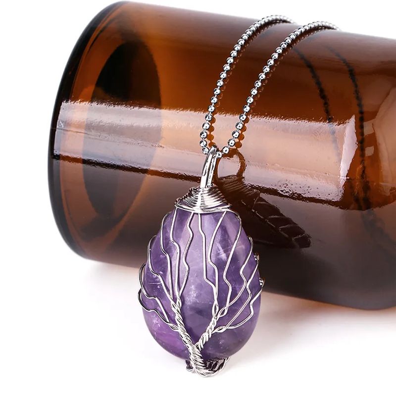 Collier pendentif avec chaine à billes et arbre de vie en cuivre plaqué platine - pierre naturelle de forme goutte d'eau en améthyste violette, le tout reposant autour d'une bouteille couchée en verre de couleur café