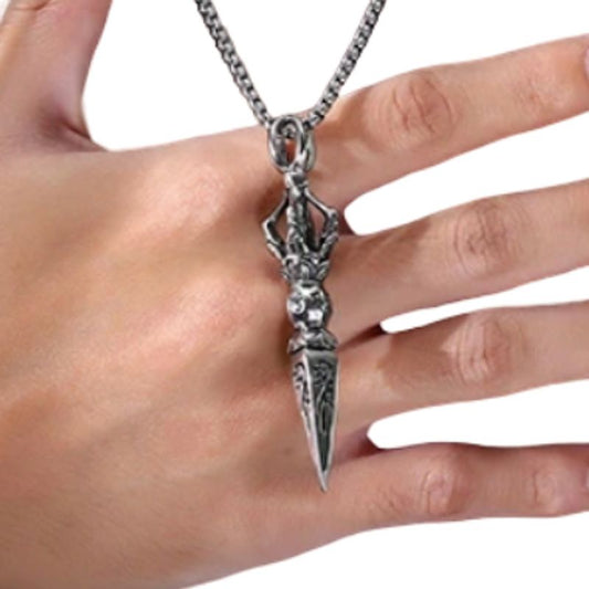 Vue d'un collier tibétain posé sur le dessus d'une main d'homme, son pendentif à dague phurba vajra est en acier inoxydable comme également sa chaine à maillons vénitien - coloris argent