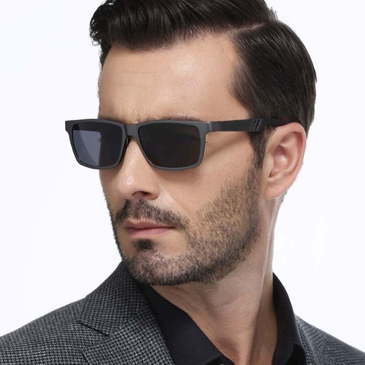 Lunettes de soleil Marcus de style Voyageur sur le nez d'un bel homme moderne élégant avec barbe de trois jours, sa tête est légèrement tourné vers la droite, ce qui permet de voir la largeur et le design masculin de la branche noire et grise incurvée - lunettes polarisées parfaitement ajustées