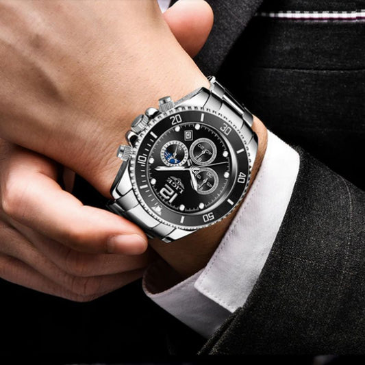 Montre de sport chronographe au poignet d'un homme en costume et chemise blanche, ses trois sous-cadrans sont fonctionnels et son bracelet est en acier inoxydable - cadran coloris noir