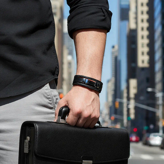 Gros plan saisissant sur le bracelet Éclipse en cuir noir texturé et agate, porté avec assurance au poignet d'un homme tenant un attaché-case, son design multi-rangs reflétant l'énergie d'une avenue urbaine baignée de lumière.