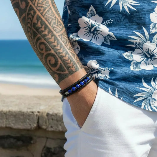 Zoom détaillé sur le bracelet Azur porté au poignet, révélant la souplesse des lanières tressées et l'élégance des six perles lapis-lazuli devant un panorama côtier ensoleillé.