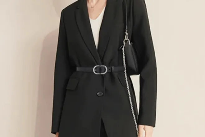 Plan large d'une femme portant par dessus sa veste une ceinture Rita en cuir noir