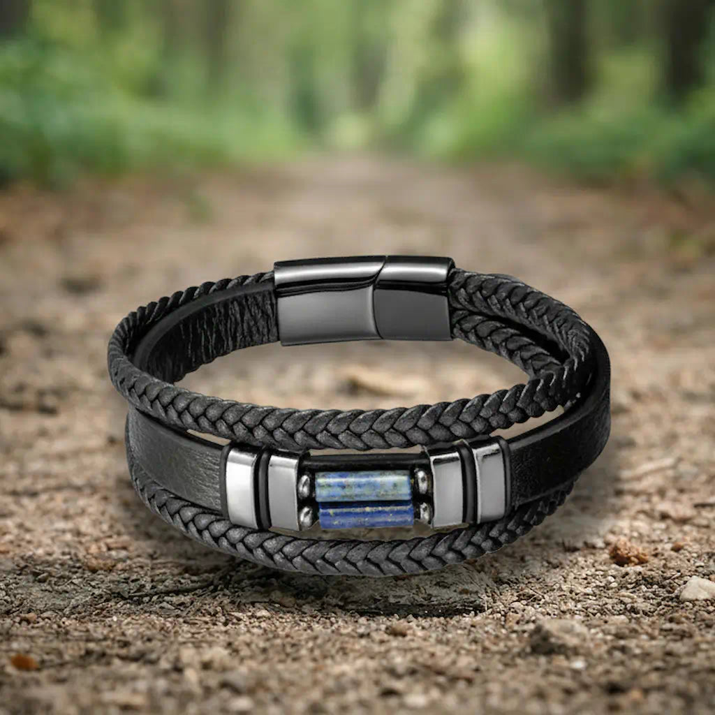 Le bracelet Azimut repose délicatement sur le sol d'un sentier de randonnée, capturant la lumière douce de la forêt sur ses pierres bleues et son architecture multi-rangs sophistiquée.
