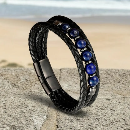 Bracelet Azur légèrement incliné en équilibre sur un parapet, capturant la lumière naturelle sur les nuances bleu outremer des pierres et la finition gunmetal du fermoir en acier inoxydable.