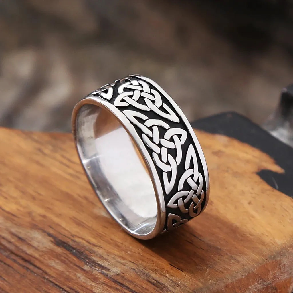 Bague pour homme avec nœud celtique en acier inoxydable argenté et noir – anneau viking posé sur une table en bois rustique.