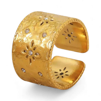 Gros plan d’une bague Aura en acier inoxydable fusion or. Ce bijou floral ouvert et ajouré dévoile un éclat de cristal central sur un fond blanc épuré.