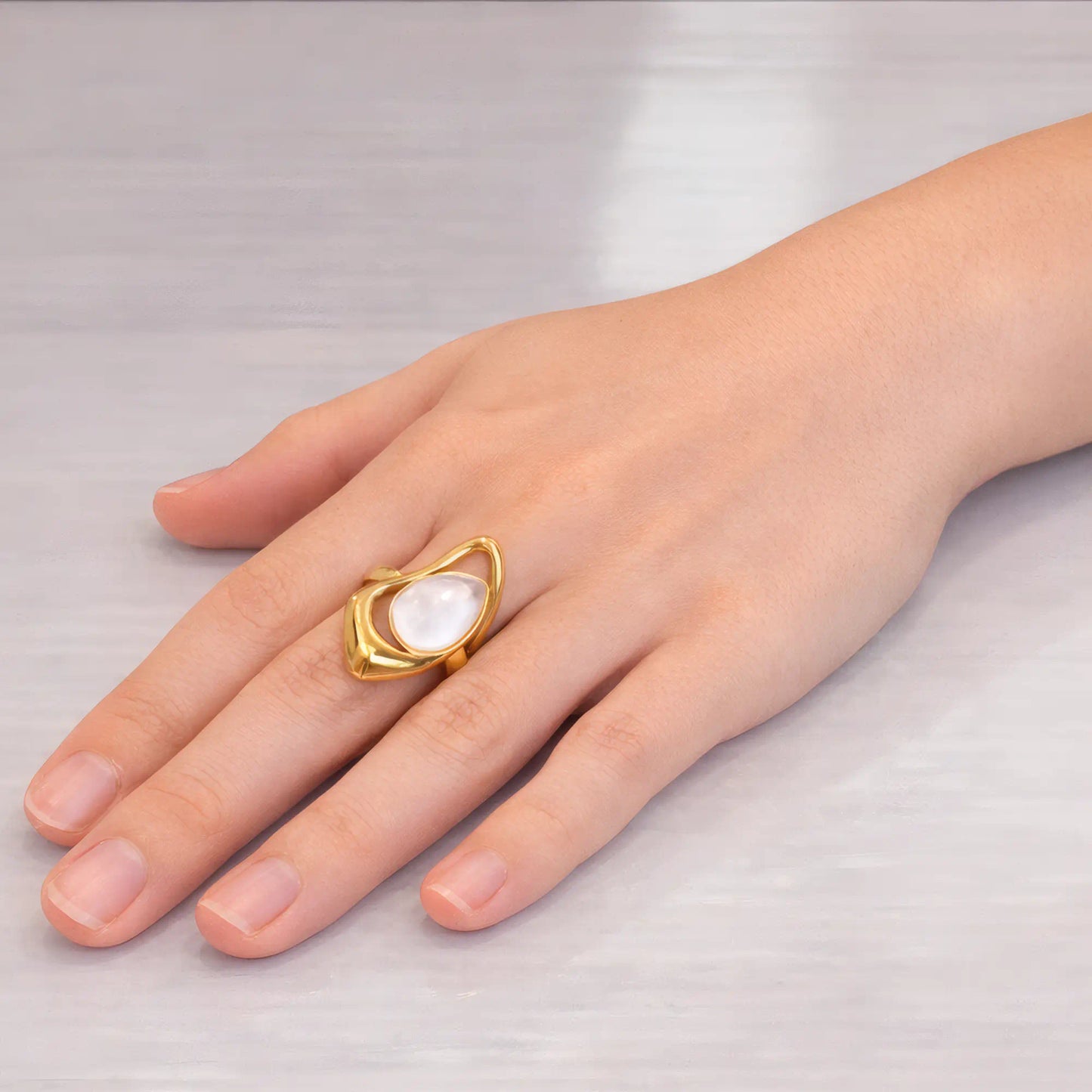 Bague Femme Dorée Nacre Portée Doigt Majeur Main Femme Posée Plat Comptoir Blanc Vitrifié Mira Akrochic