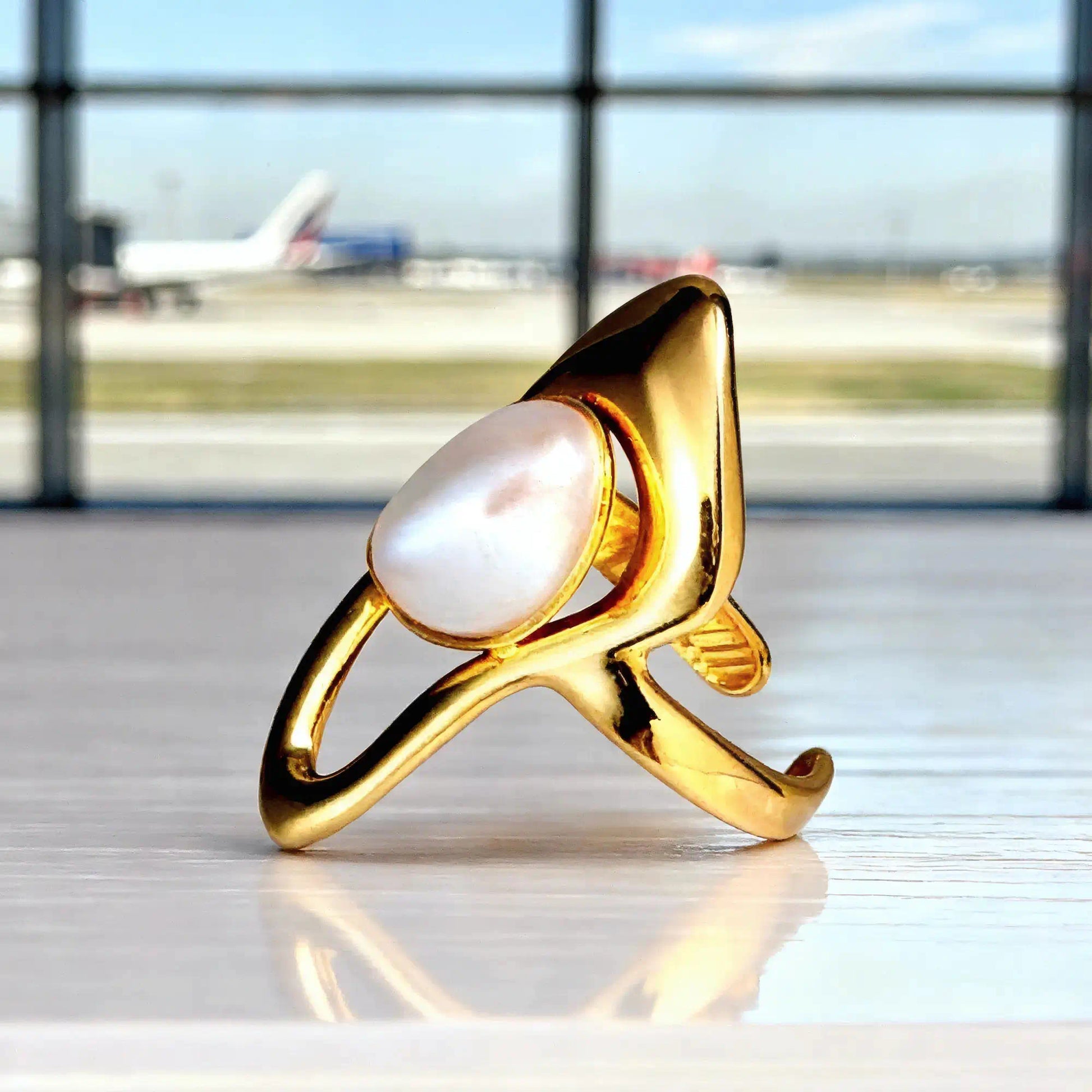 Bague Dorée Nacre Voyage Ambiance Aéroport Posée Comptoir Blanc Vitrifié Fond Flouté Avion Mira Akrochic