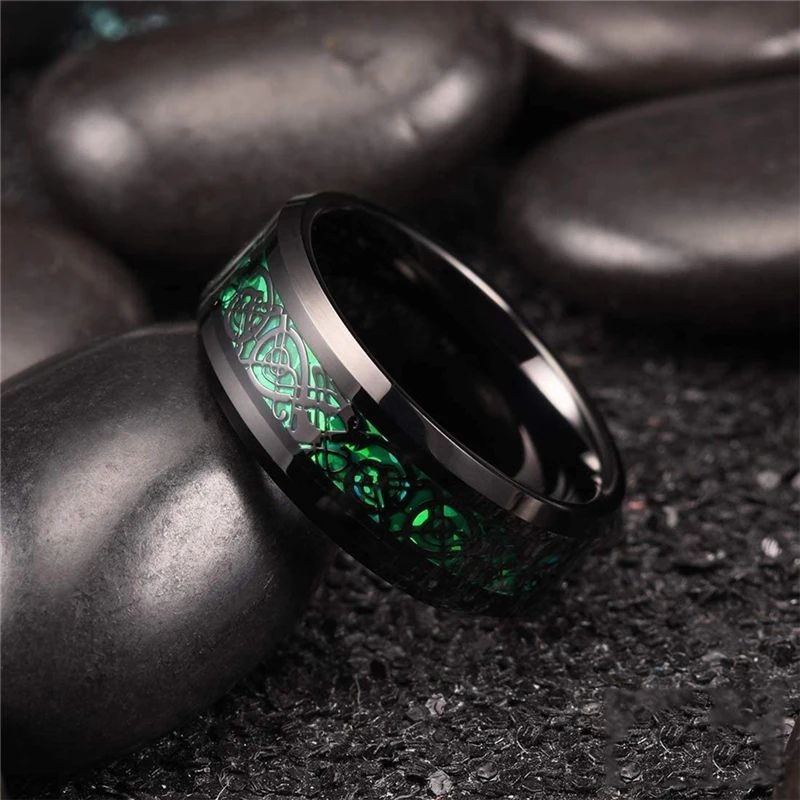 Bague Dragon Celte pour homme en acier inoxydable, anneau présenté, inclinée, posée sur un galet lisse de couleur noir – coloris noir et vert.