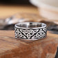 Bague en acier inoxydable pour homme, motif nœud celte de couleur argent sur fond noir. Présentation de l'anneau viking sur un large et épais plan de travail en bois.