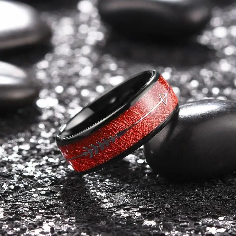 Bague Flèche Egil pour homme en acier inoxydable, anneau présenté, inclinée, posée sur un galet lisse de couleur noir – coloris noir et rouge.