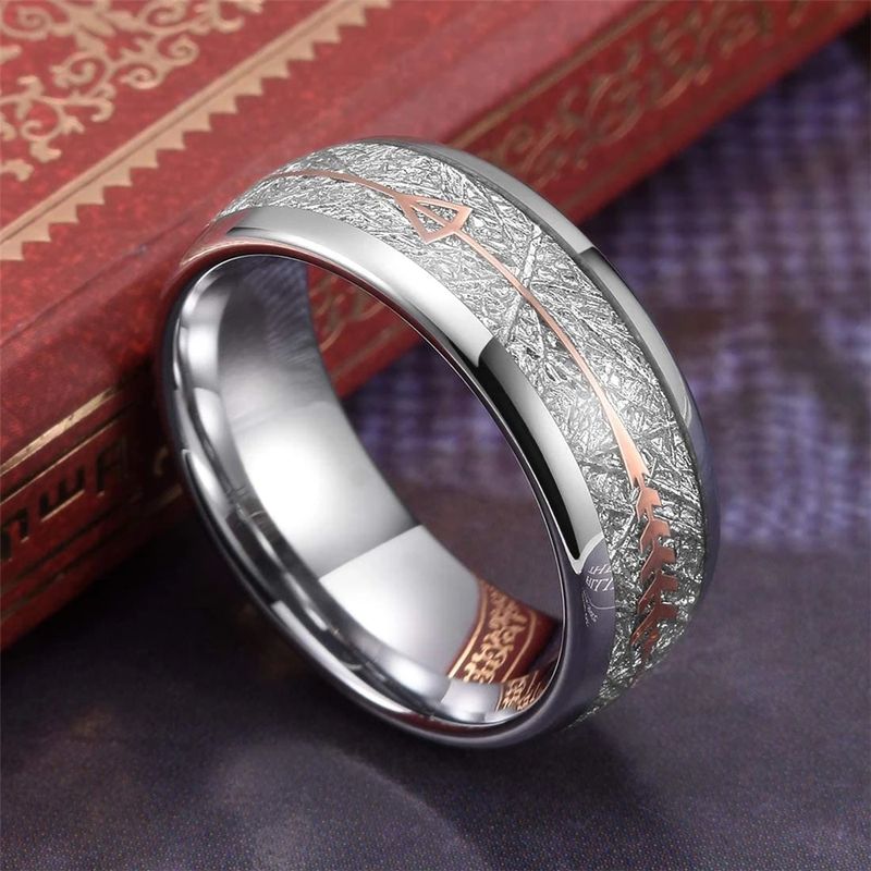 Bague Flèche Egil pour homme en acier inoxydable, anneau dressé, contre un livre à la reliure en cuir rouge sur un plan de travail noir – coloris argent.