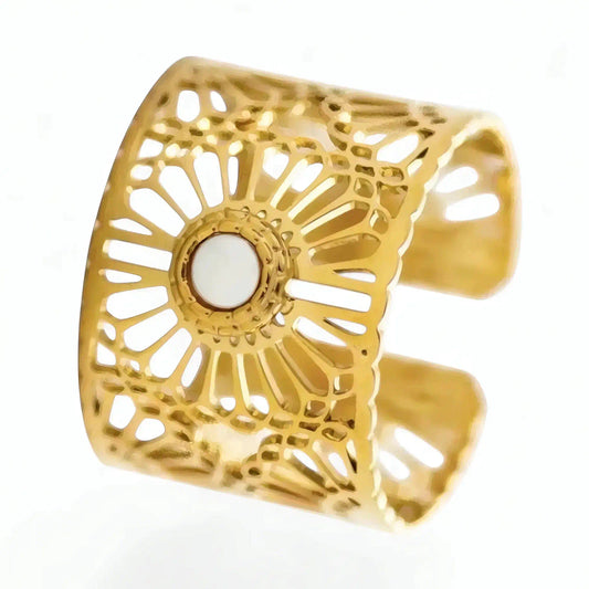 Bague Lyna ajustable acier inoxydable fusion or gros plan 3/4 face motif solaire ajouré cabochon nacre blanc structure large fond studio neutre.