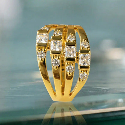 Silhouette de profil de la bague Lyra en plaqué or 14K en équilibre sur une surface vitrée. Les quatre demi-rangs soutiennent un sertissage avec barrette où rayonnent douze zircones blanches.