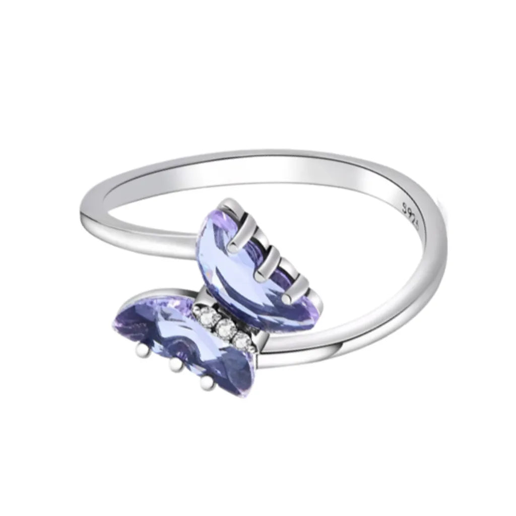 Bague en argent 925 ornée d’un délicat papillon en cristal violet, agrémentée de petites pierres en zircone scintillantes. La bague présente un design minimaliste élégant avec un fond blanc épuré.