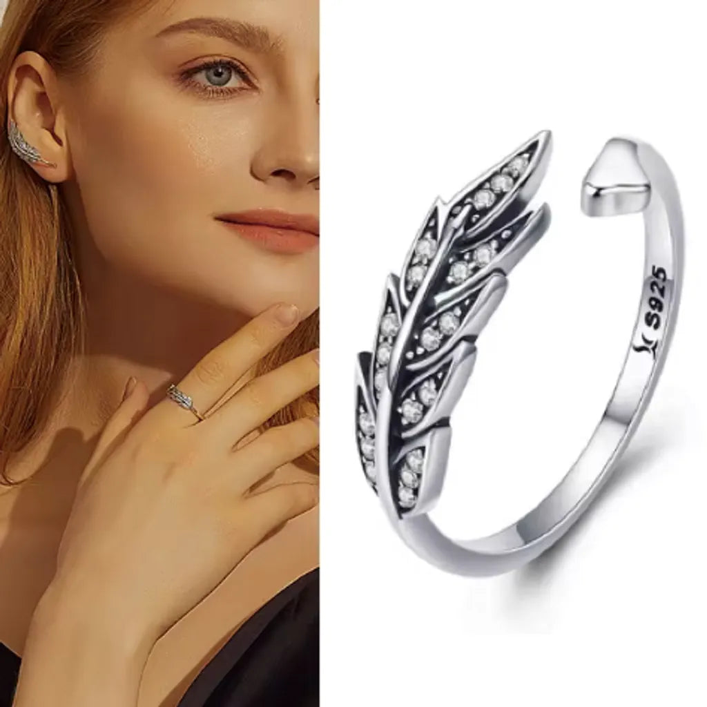 Bague plume Crécerelle en argent 925 avec zircones, présentée sous deux aspects : Vue portée sur une femme élégante, sublimant la délicatesse et la finesse du design plume sur un doigt fin. Vue détaillée en gros plan de la bague, révélant les zircones étincelantes parfaitement serties et la forme ouverte moderne en argent 925.