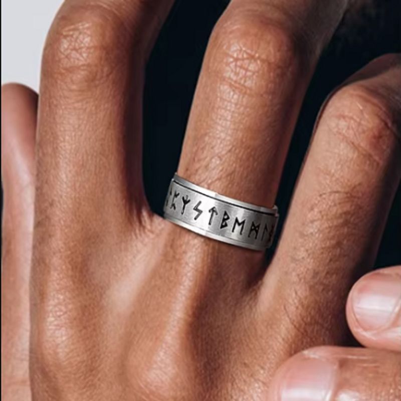 Bague Rune Viking rotative en acier inoxydable autour du doigt majeur d'une main gauche d'un homme – coloris argent.